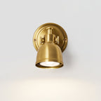 Front view of this Clérachic wall light, its round backplate behind a brushed gold dome with the bulb lit and a glow below on grey.