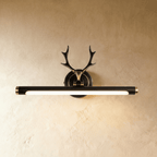Clérachic antler wall light in dark bronze black with gold end caps and a lit 43 cm tube, on a warm limewash wall.