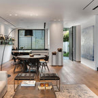 Black Clérachic arc floor lamp reaching over a round dining table in an open-plan kitchen and living room.