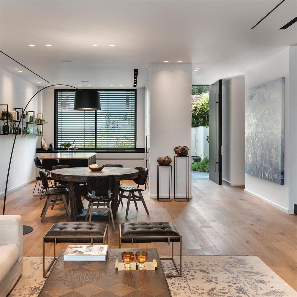 Black Clérachic arc floor lamp reaching over a round dining table in an open-plan kitchen and living room.