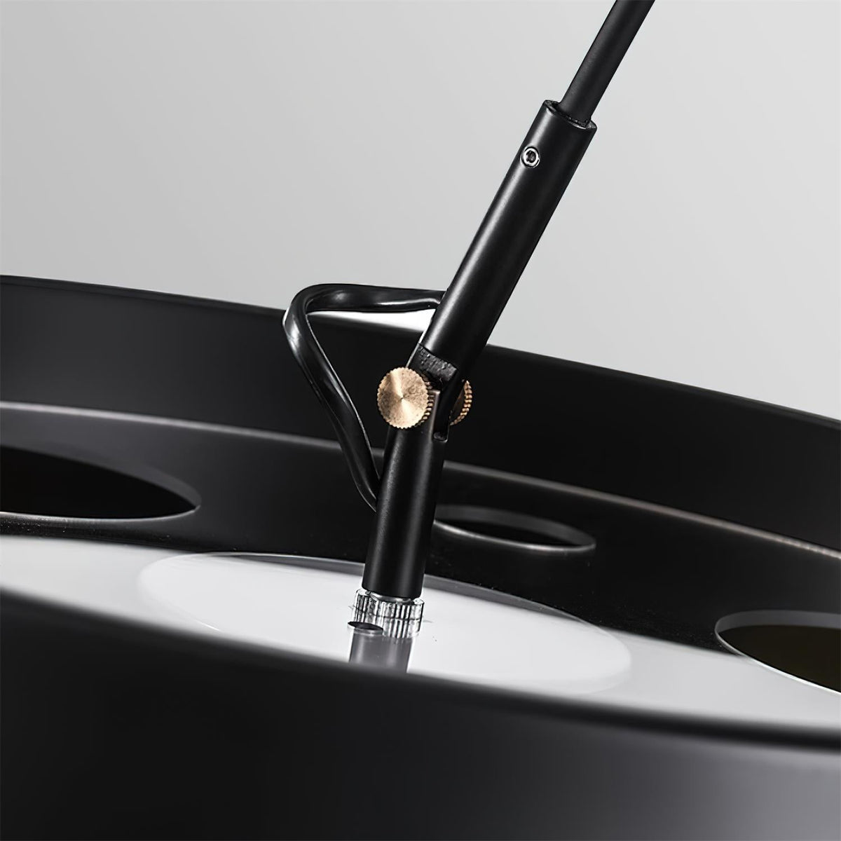 Close view of the joint where the arm meets the shade on this Clérachic arc floor lamp, with a small gold-toned knob.