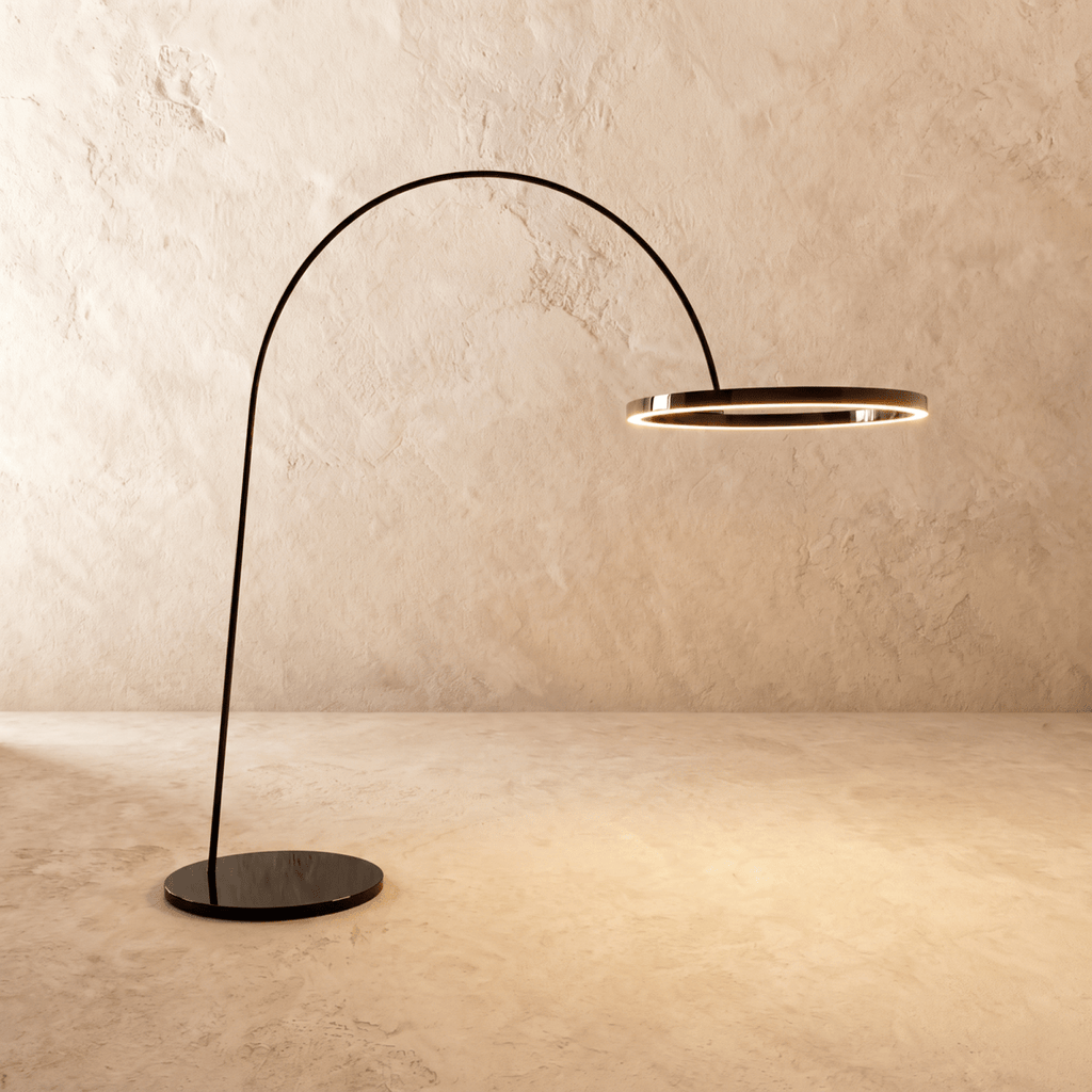 Clérachic taller arc floor lamp with a glossy black ring and round black base, the ring edge lit with a warm line.