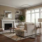 In a living room with a white fireplace and tall windows, a Clérachic chrome arc lamp reaches across a cream sofa.