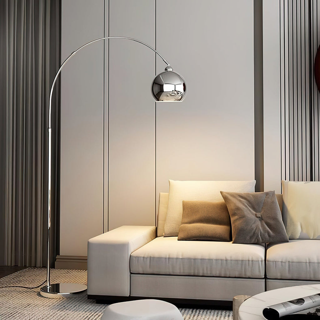 A tall Clérachic arc lamp with a chrome ball head stands beside a cream sectional with taupe cushions and pleated curtains.