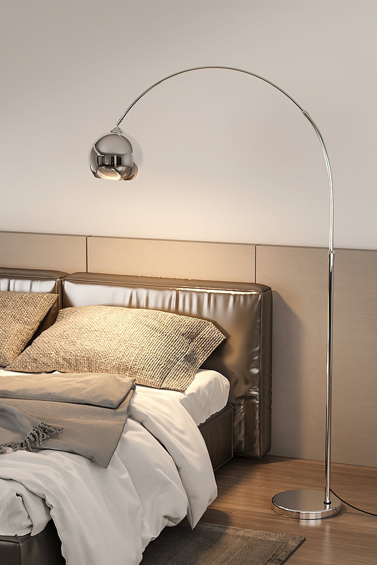 A chrome arc lamp from Clérachic leans in above a bed with a quilted headboard, textured pillows and grey bedding.