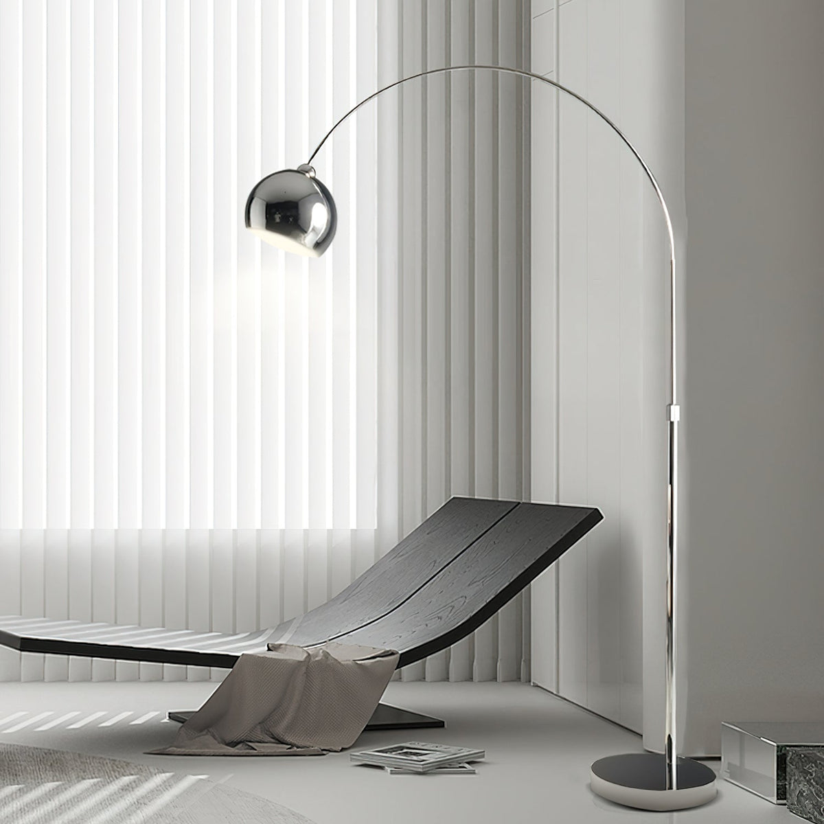 A Clérachic arc lamp curves over a dark lounger with a grey throw, in front of white vertical blinds.
