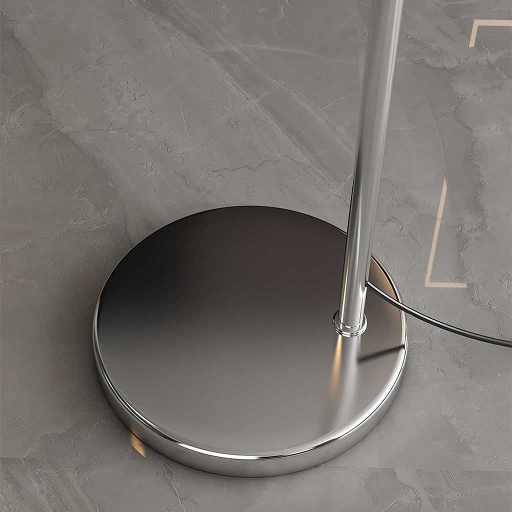 Close view of the round chrome base of this Clérachic arc lamp, with the stem rising from it and the cord leaving the side.