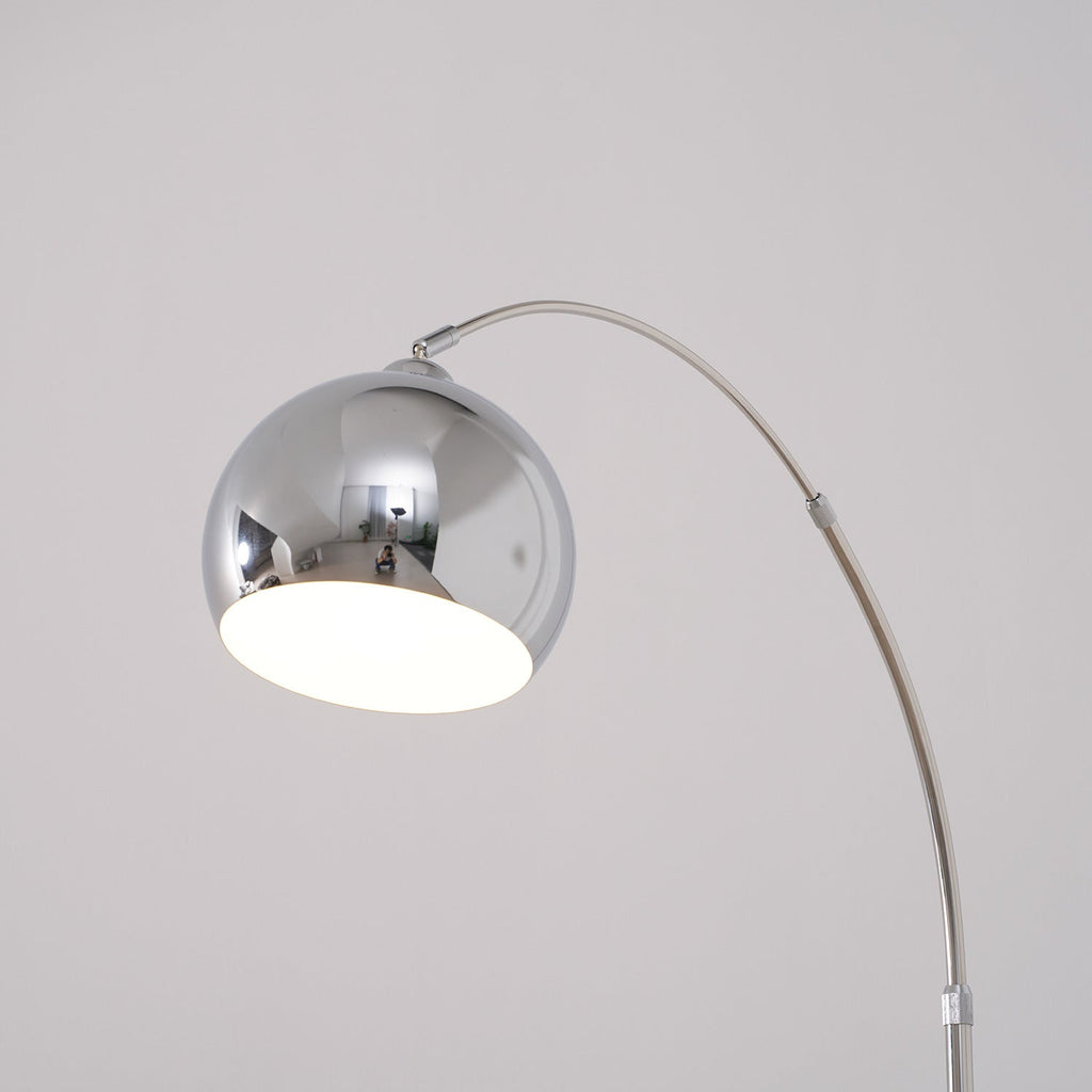 Close view of the round chrome head on this Clérachic arc lamp, with a white inner shade and the arm curving away.