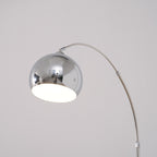 Close view of the round chrome head on this Clérachic arc lamp, with a white inner shade and the arm curving away.