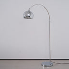A Clérachic chrome arc floor lamp with a round base and a black cord, on a pale grey background.