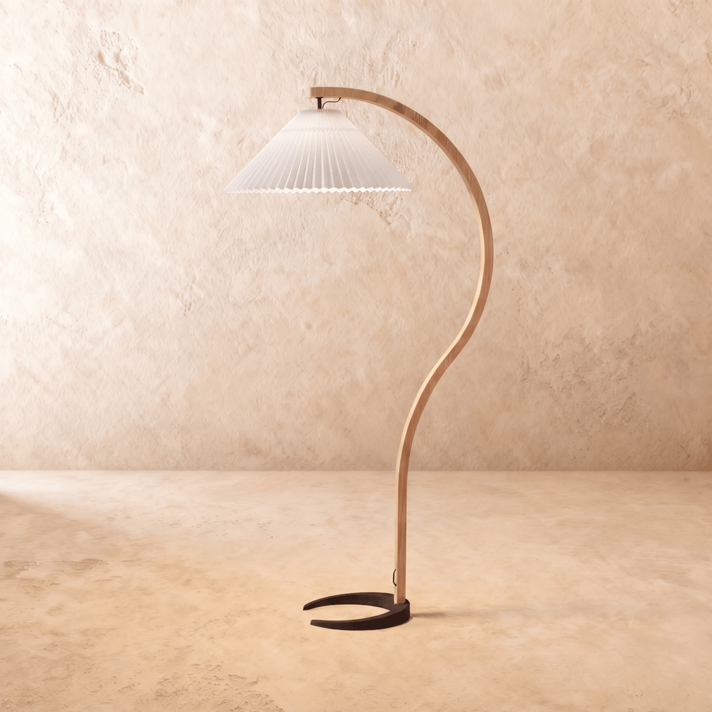 Clérachic arched floor lamp with a bent light-wood stem, black horseshoe base and a white pleated shade on limewash.