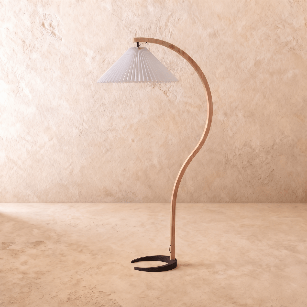 Clérachic arched floor lamp in a cool white pleated shade, with a curved pale-wood stem and horseshoe base on plaster.