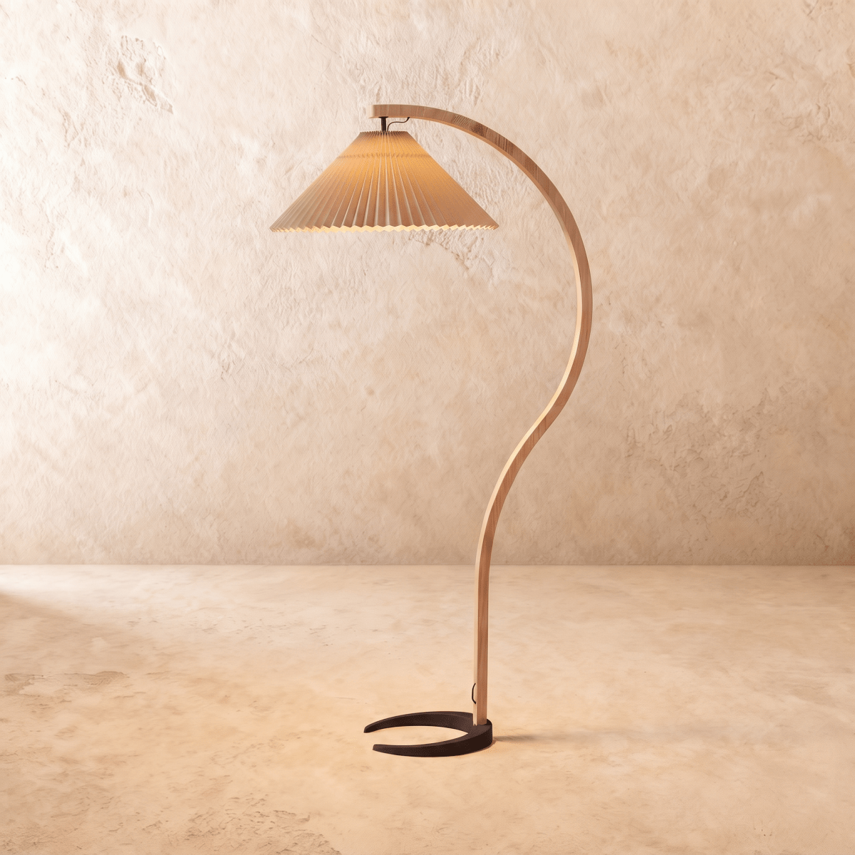 Clérachic arched floor lamp with a deeper tan pleated shade, curved wooden stem and dark horseshoe base on plaster.