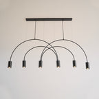 Front view of this Clérachic arch pendant in black, six spot heads below a slim canopy bar on a pale wall.