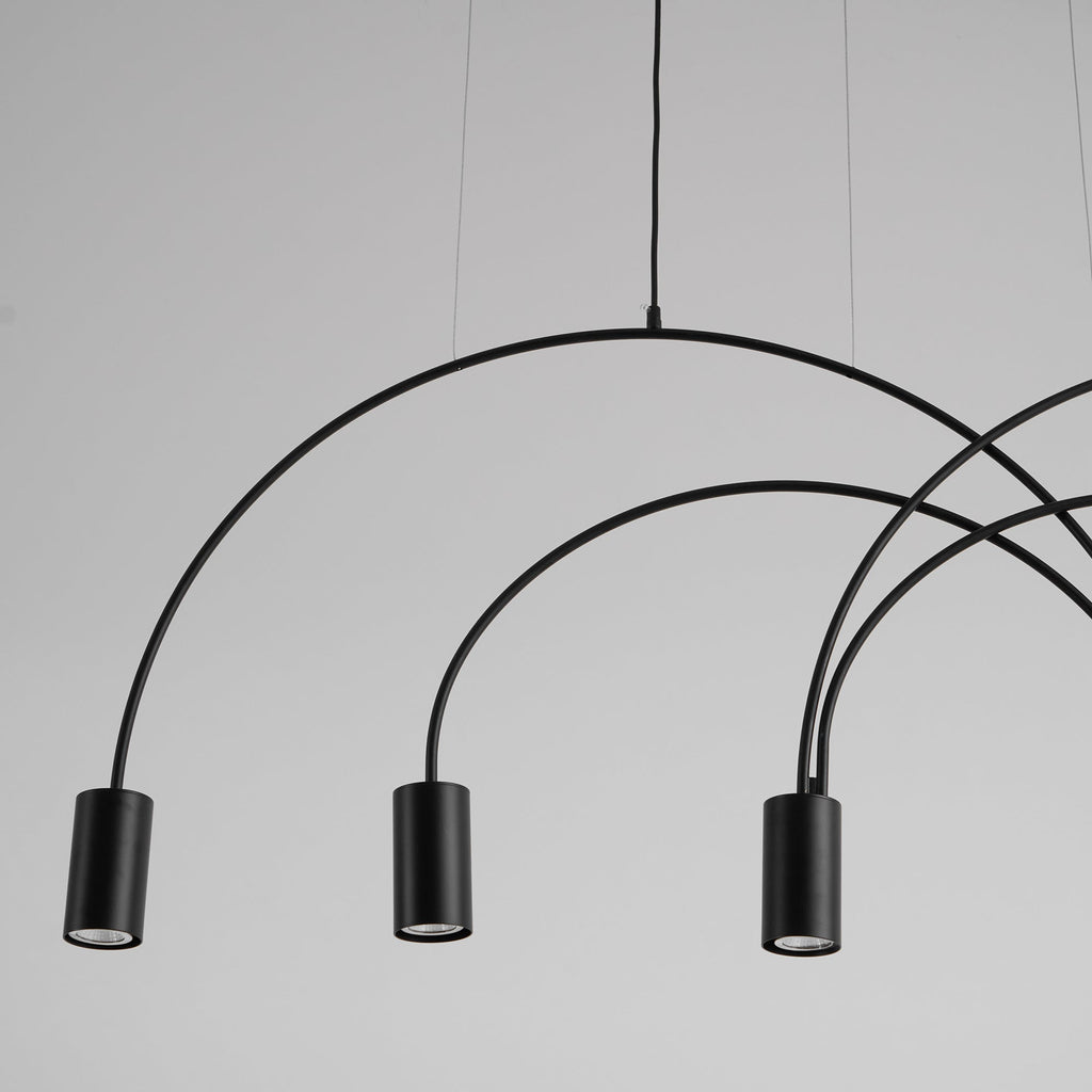 Close view of three black cylindrical spot heads and the thin round arches that carry them on this Clérachic pendant.