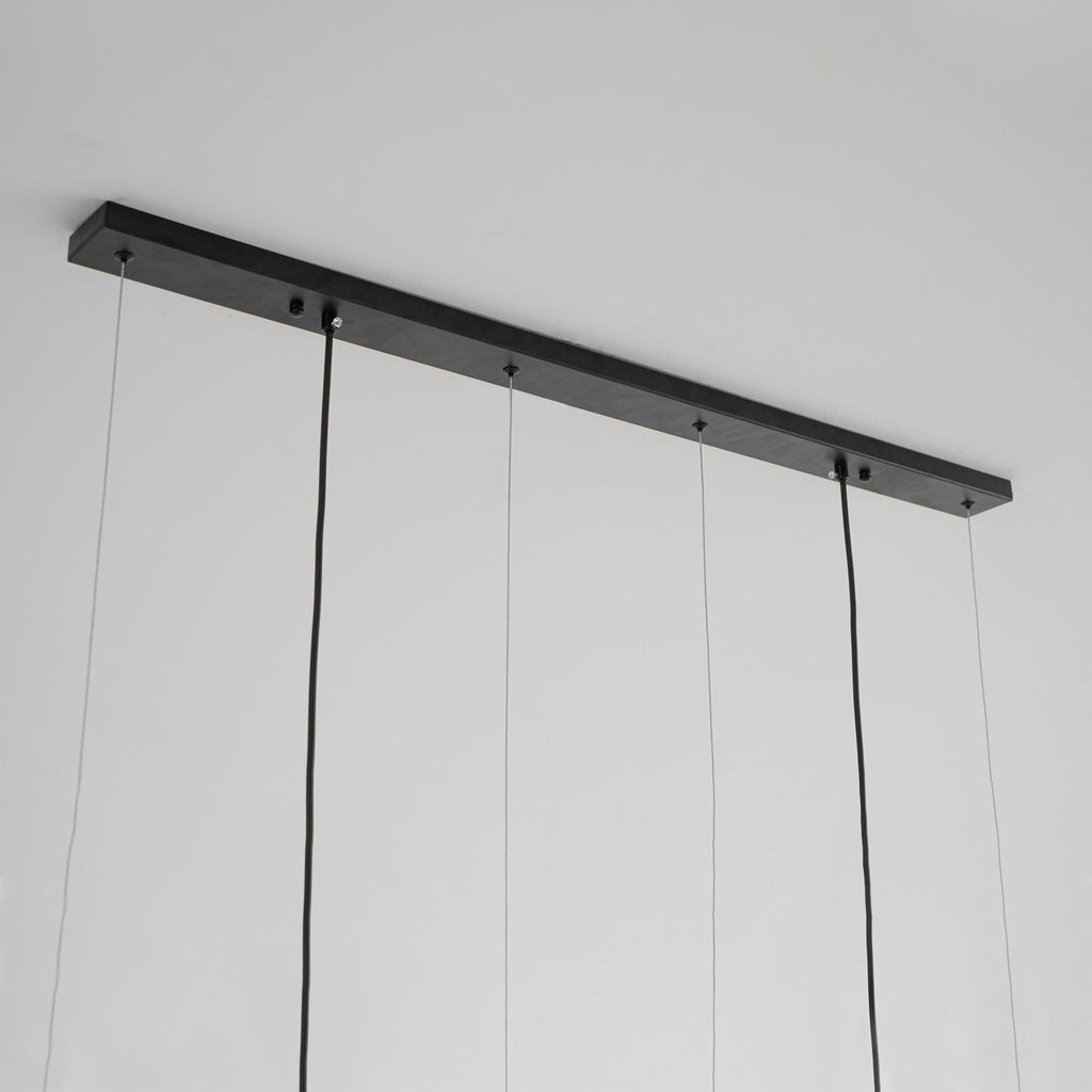 Underside of the slim black canopy bar on this Clérachic pendant, with fine suspension wires and two thicker power cords.