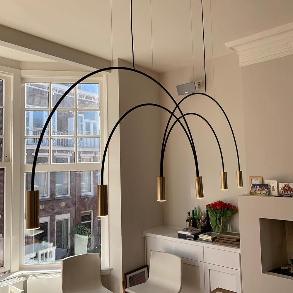 Long black arches and brass spot heads sweep out from this Clérachic pendant in a bay-window room with a fireplace.
