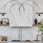 Brass spot heads on black arches, this Clérachic pendant spans a marble kitchen wall with open shelves and ceramics.