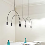 Black Clérachic arches and spot heads hang at different heights in a cream room with cornices, above a white table.