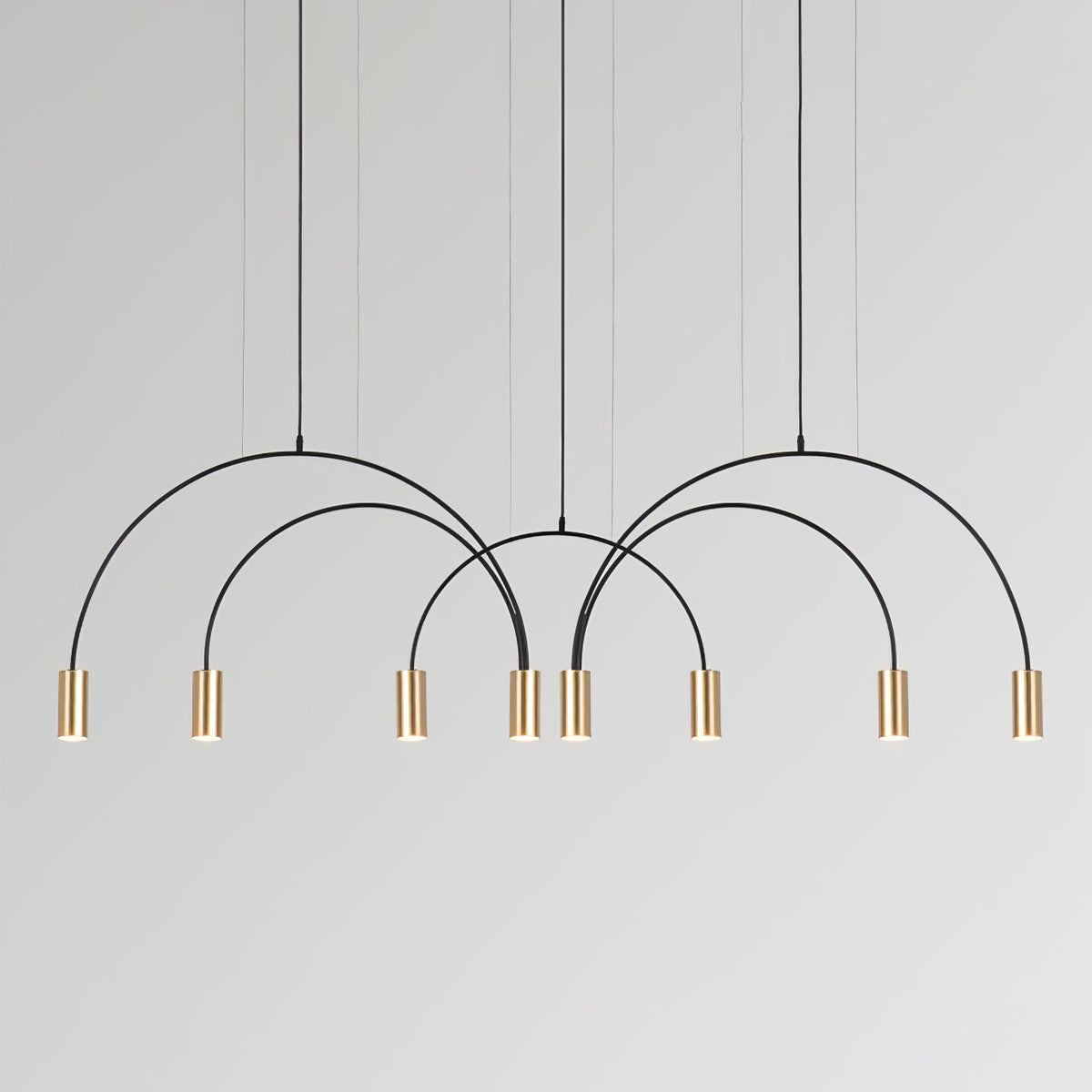 Eight brass spot heads hang from four black arches on this Clérachic pendant, against a pale grey backdrop.