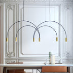 Against an ornate white panelled wall, this Clérachic arch pendant carries brass spot heads above a white table.
