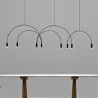Black Clérachic spot heads and thin arches against a grey wall, with the legs of a table just visible below.