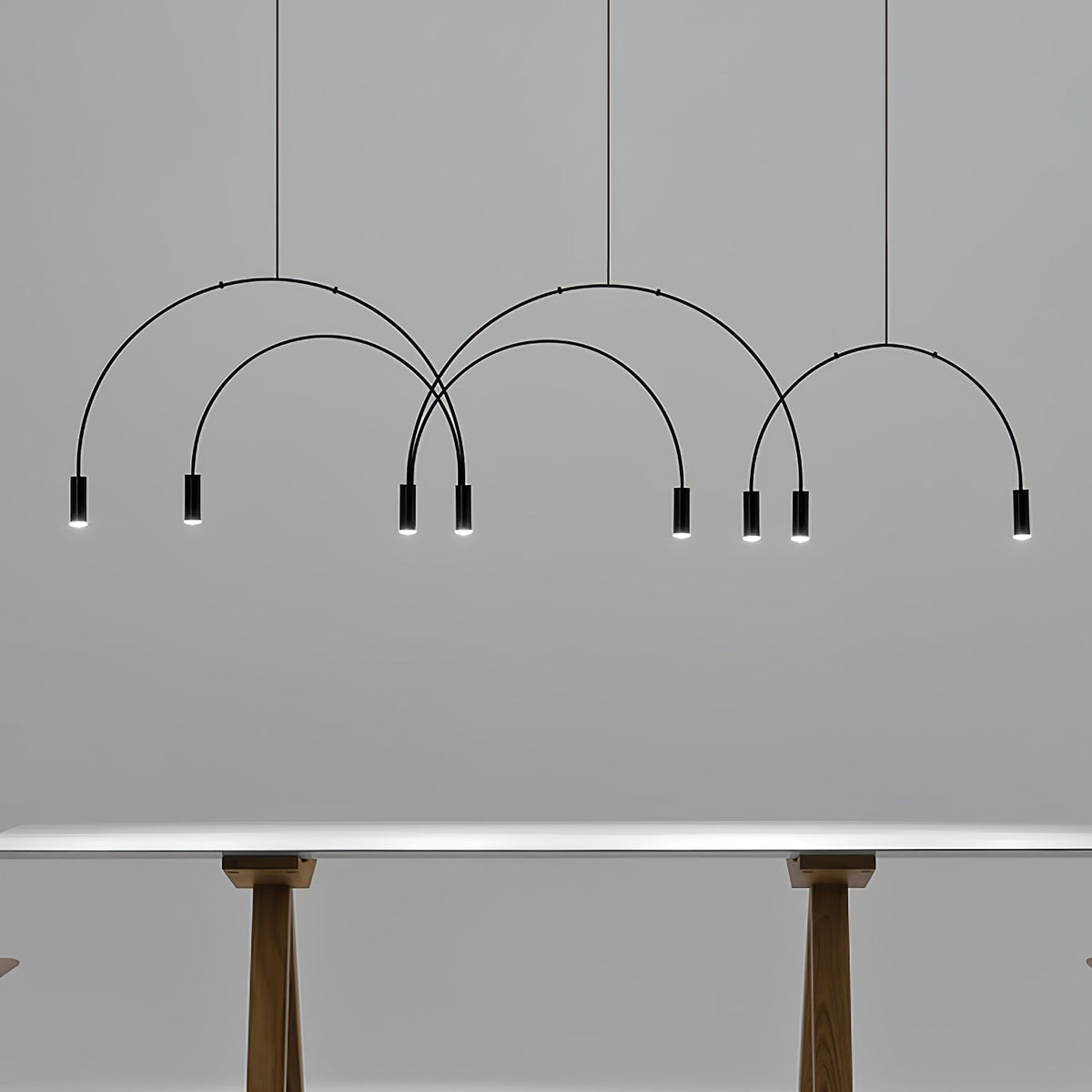 Black Clérachic spot heads and thin arches against a grey wall, with the legs of a table just visible below.