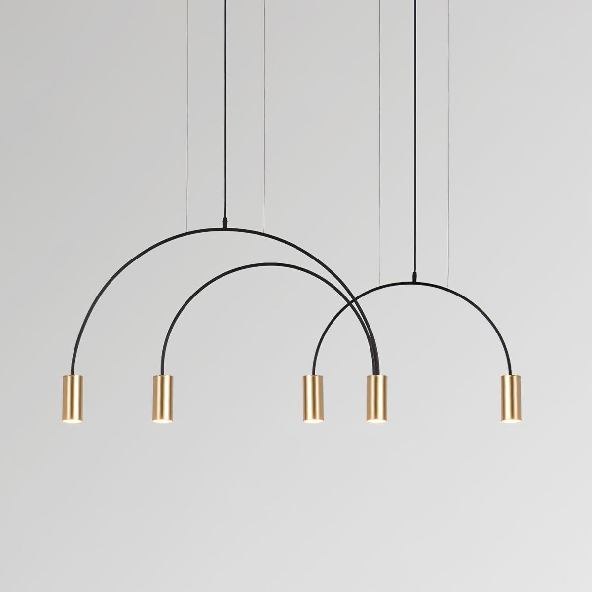 Five brass spot heads on three overlapping black arches, this Clérachic pendant on a grey backdrop.