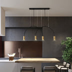 A black canopy bar and four brass spot heads on this Clérachic pendant, over a wooden counter in a dark grey kitchen.