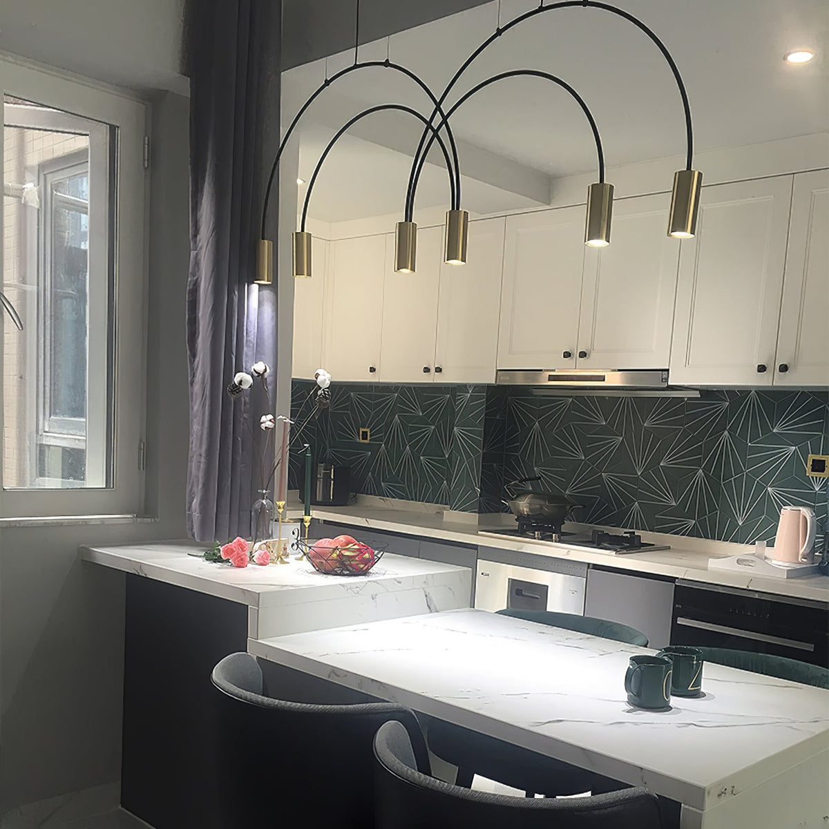 Brass spot heads on tall black arches, this Clérachic pendant hangs in a white kitchen with a green geometric splashback.