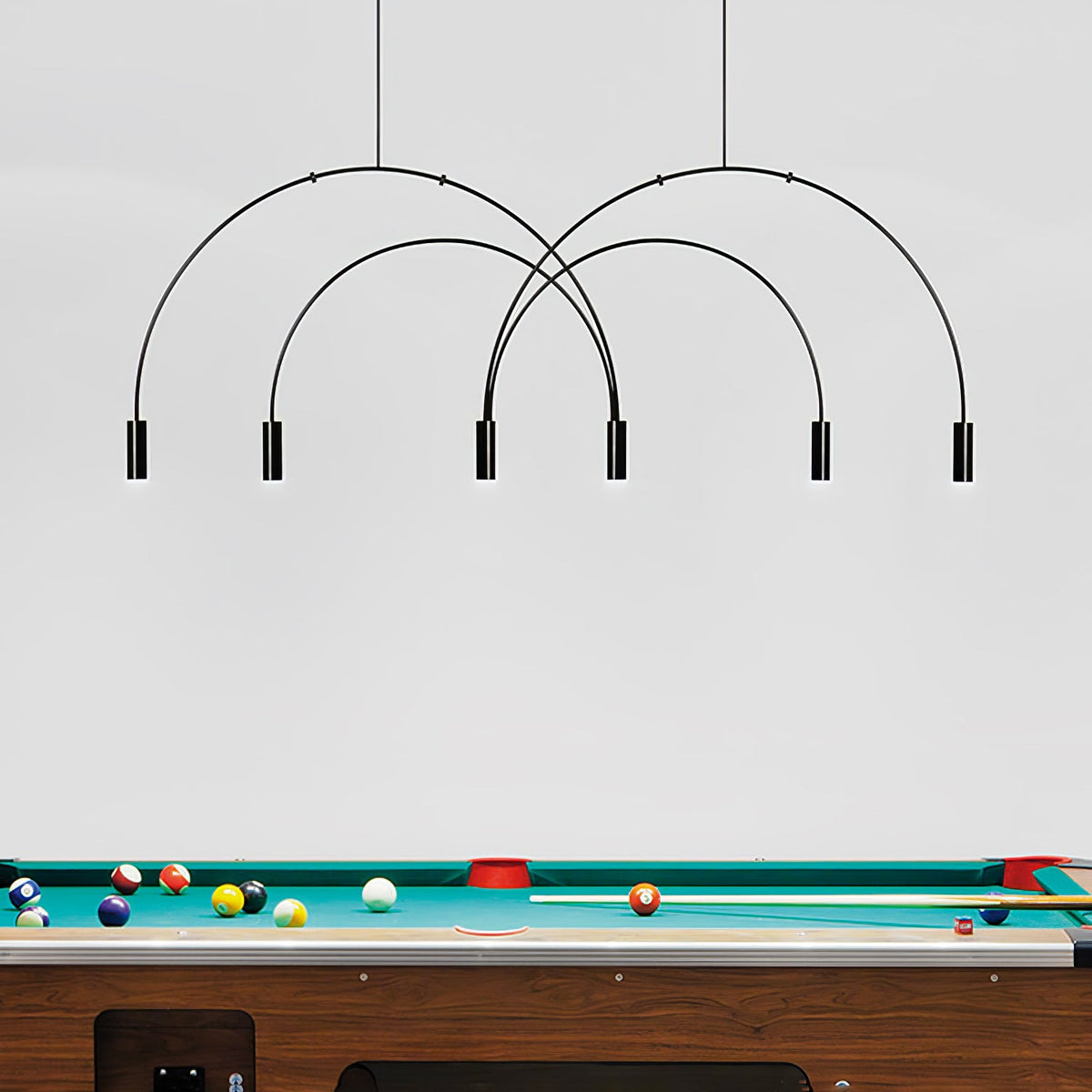 Six black spot heads hang from overlapping arches on this Clérachic pendant, placed above a green-baize pool table.