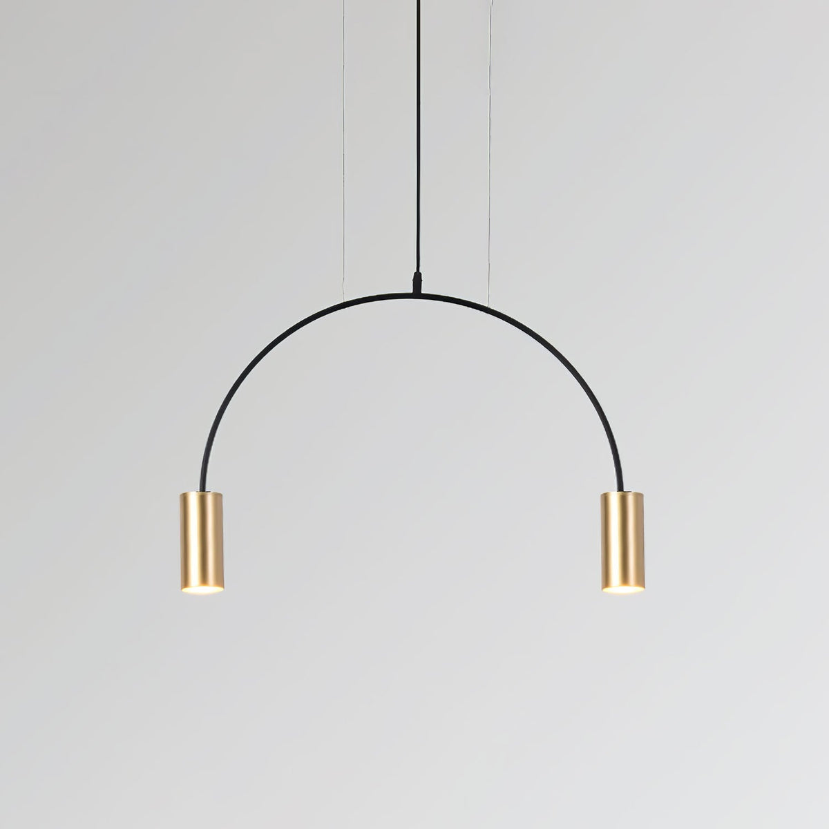 A single black arch carries two brass spot heads on this Clérachic pendant, on a pale grey backdrop.