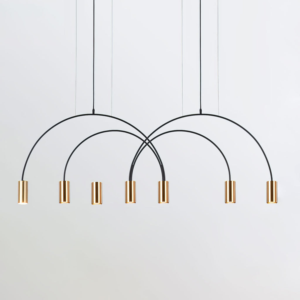 A cluster of brass spot heads hangs under crossing black arches on this Clérachic pendant, on a light grey backdrop.