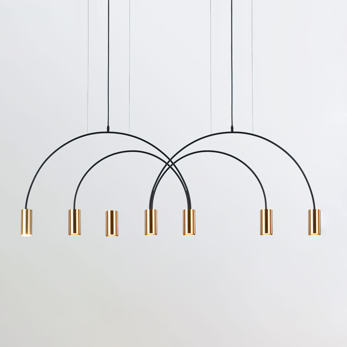 A cluster of brass spot heads hangs under crossing black arches on this Clérachic pendant, on a light grey backdrop.