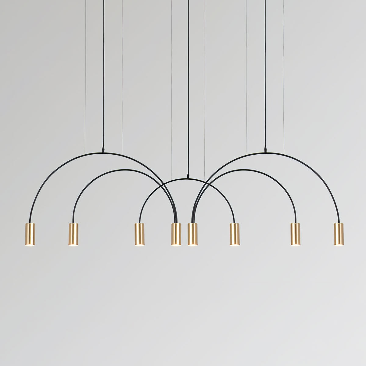 Eight brass spot heads on interlocking black arches, this Clérachic pendant on a pale grey backdrop.