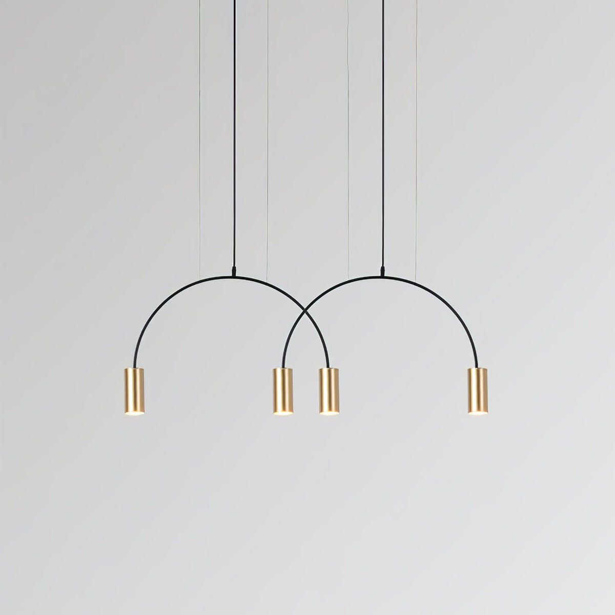 Two black arches and four brass spot heads, this Clérachic pendant on a light grey backdrop.
