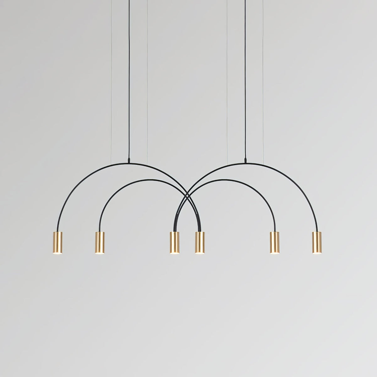 Six brass spot heads hang in an even row beneath the crossing black arches of this Clérachic pendant.