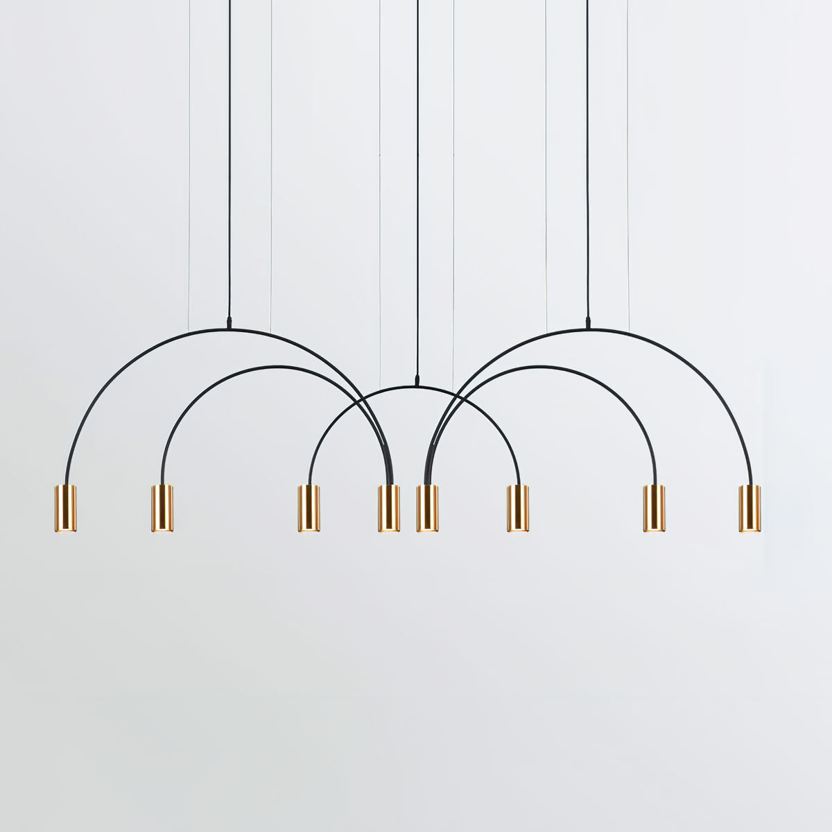 Eight brass spot heads hang from four black arches on this Clérachic pendant, on a pale grey backdrop.