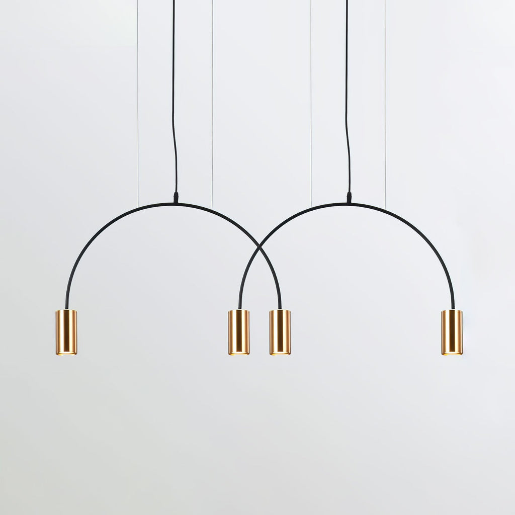 Two black arches and four brass spot heads, this Clérachic pendant seen against a pale backdrop.
