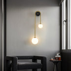Clérachic arched brass wall sconce beside a window in a grey corner, lighting an armchair and a small drinks table.
