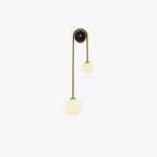 Clérachic arched brass wall sconce shown unlit, the milk-white globes flat matte against an off-white background.