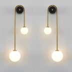 A left and a right Clérachic arched brass wall sconce lit side by side, mirrored to flank a bed or a mirror.