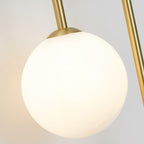 Close-up of the larger frosted globe on the Clérachic arched brass wall sconce, capped in brushed brass.