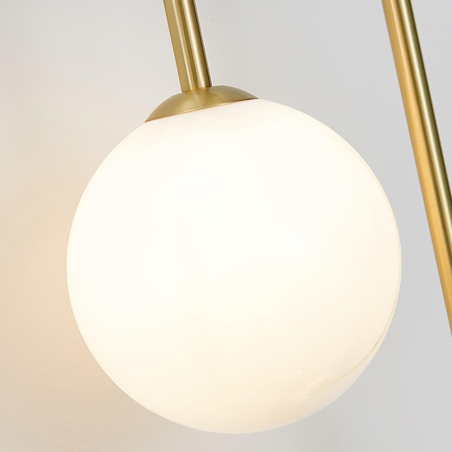 Close-up of the larger frosted globe on the Clérachic arched brass wall sconce, capped in brushed brass.