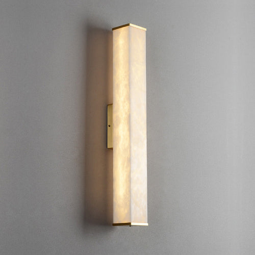 The Clérachic sconce in its squared profile, brass end caps and mounting bar crisp against a soft grey wall.