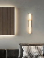 The Clérachic sconce as a slim vertical accent above a velvet sofa, alongside a backlit walnut wall panel.