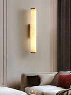 Clérachic alabaster sconce on a panelled wall, warming a living room with herringbone drapery and a red cushion.