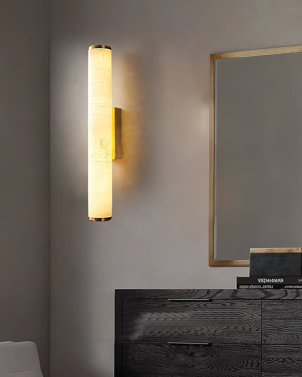 The Clérachic brass sconce beside a gilt-framed mirror, casting soft light over a dark oak dresser.