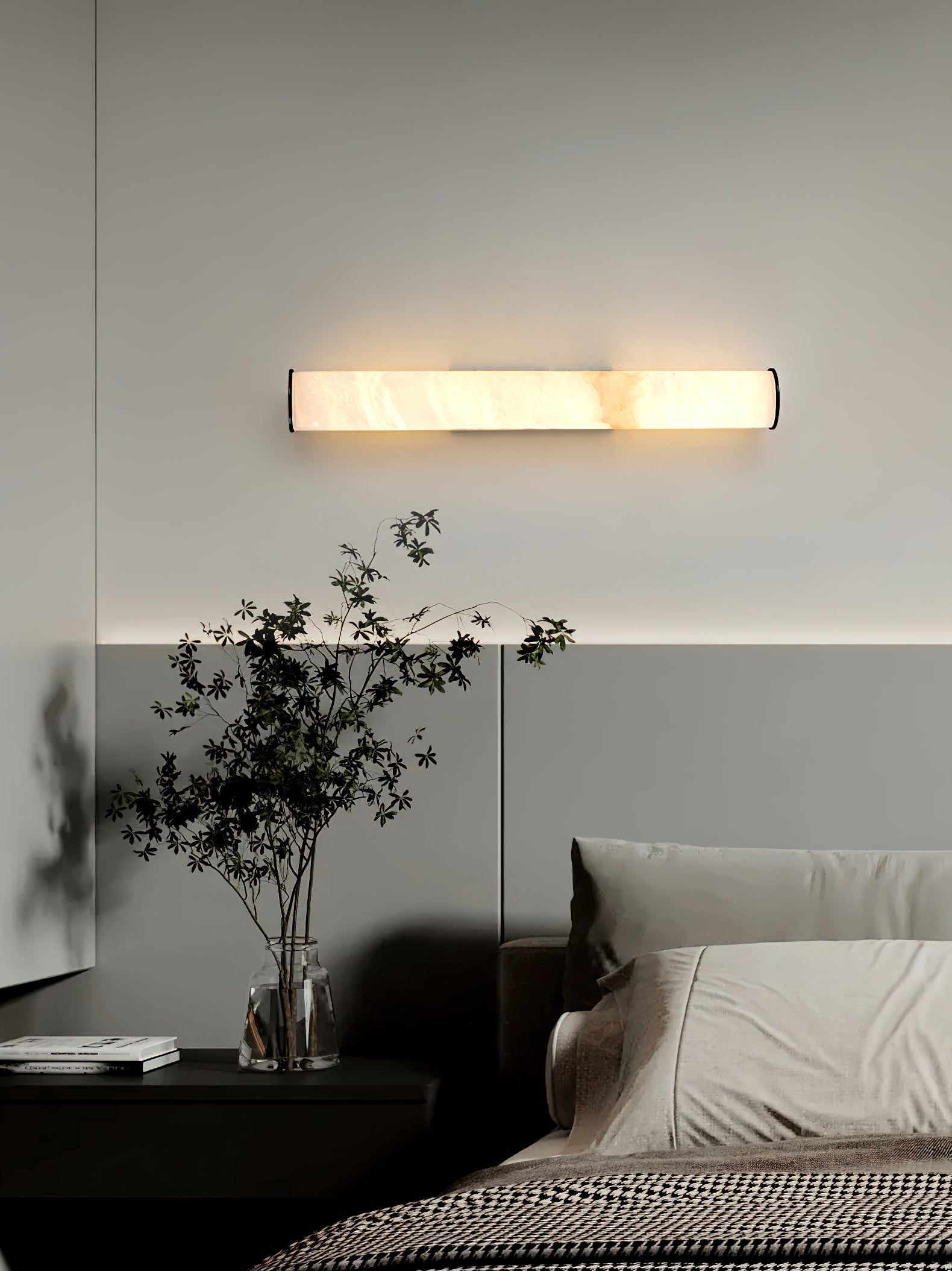 Clérachic sconce mounted horizontally above a bed, its long alabaster bar washing the headboard wall in warm light.