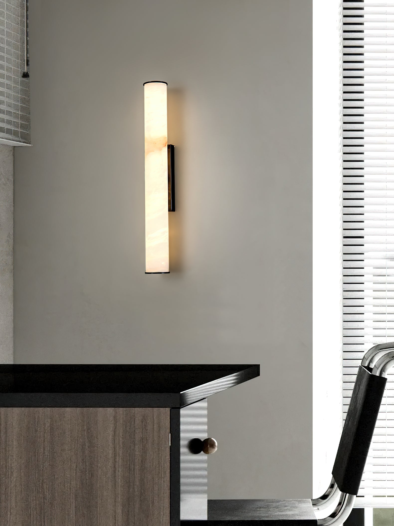 Clérachic sconce with a black bracket beside a dark timber desk, lit against louvred window blinds.